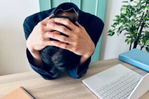 仕事について考え込み、デスクで悩んでいる人のイメージ